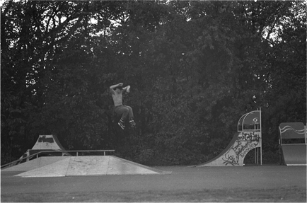 Inline skater mid-air during a 540, after launching off of a metal kicker at the skatepark.